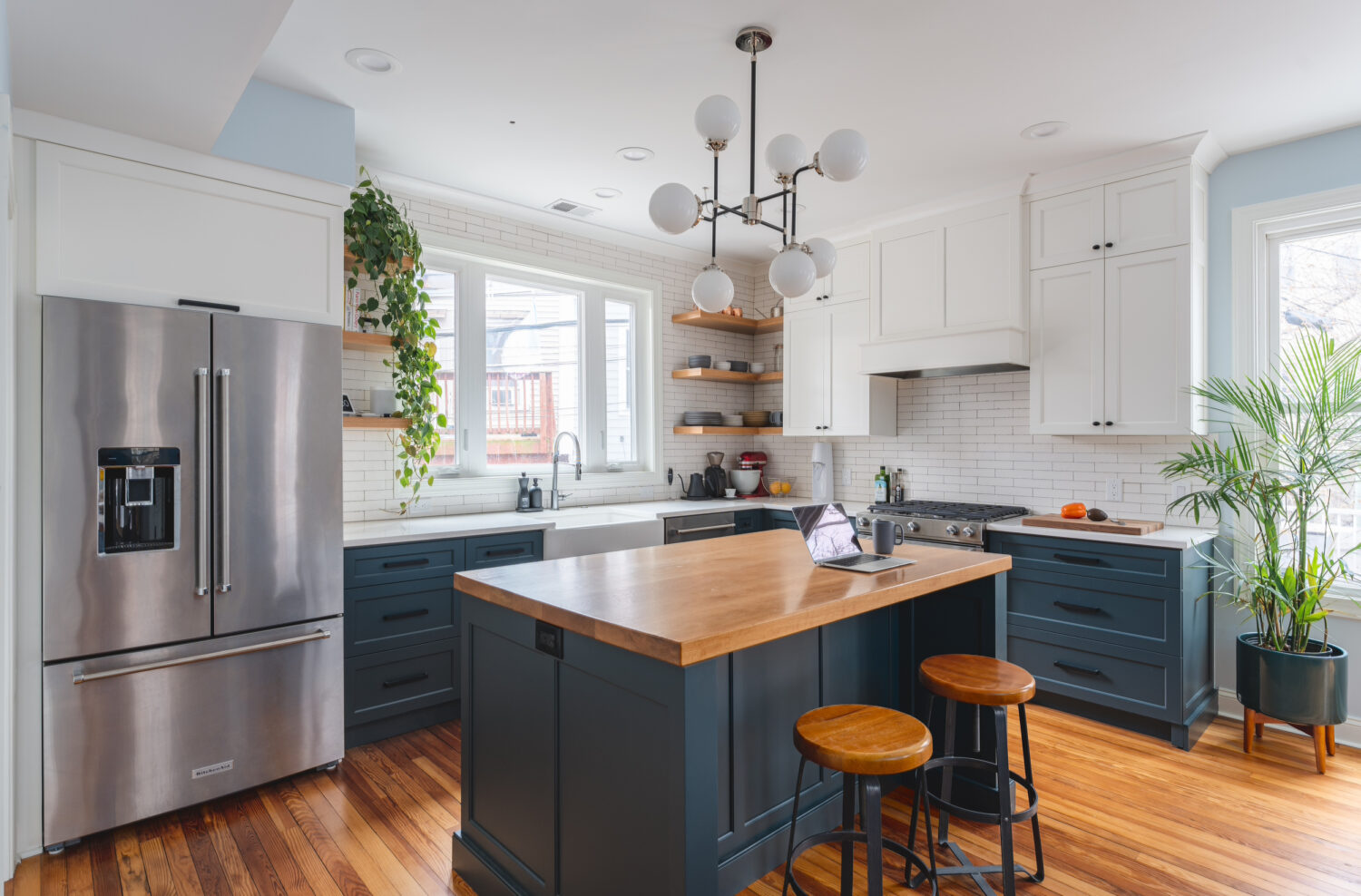 Mid-century whole home renovation in NW Washington D.C. showcasing a modern kitchen with white subway tiles, dark blue cabinets, and stylish wooden accents.